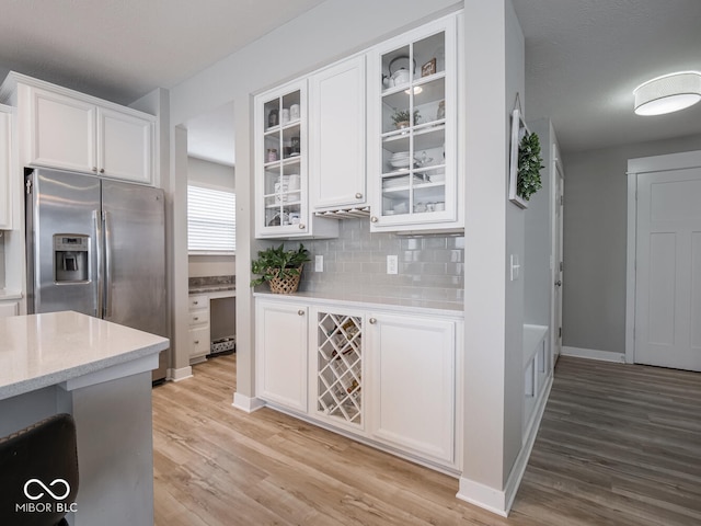 5684 Autumn Trl, Brownsburg, IN 46112 - kitchen featuring stainless steel fridge, light wood-style floors, white cabinets, backsplash, and glass insert cabinets