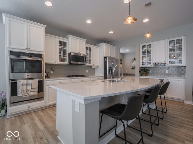 5684 Autumn Trl, Brownsburg, IN 46112 - kitchen with stainless steel appliances, a sink, decorative backsplash, white cabinetry, and light wood-type flooring