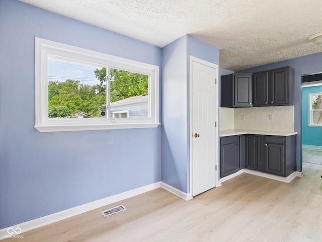 4020 N Mitthoefer Rd, Indianapolis, IN 46235 - kitchen featuring light wood-type flooring, light countertops, decorative backsplash, a textured ceiling, and baseboards