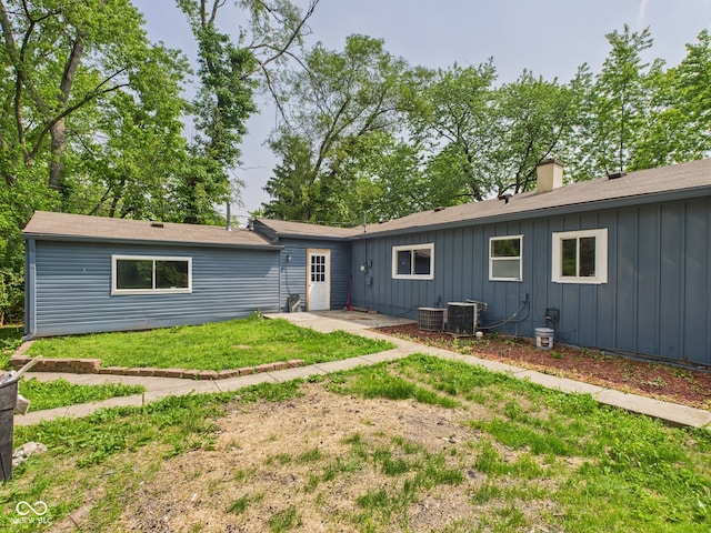 4020 N Mitthoefer Rd, Indianapolis, IN 46235 - rear view of house with a chimney, board and batten siding, a yard, central AC unit, and a patio