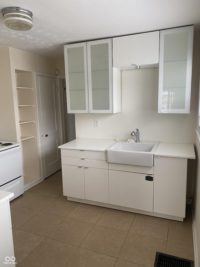 1444 N Denny St, Indianapolis, IN 46201 - kitchen with a sink, electric stove, light tile patterned flooring, and white cabinets