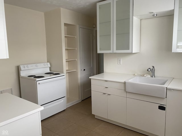 1444 N Denny St, Indianapolis, IN 46201 - kitchen with white electric stove, a sink, light tile patterned floors, and light countertops