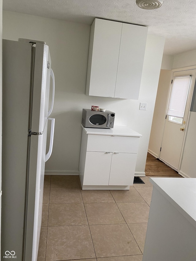 1444 N Denny St, Indianapolis, IN 46201 - kitchen featuring freestanding refrigerator, white cabinetry, light countertops, baseboards, and light tile patterned floors