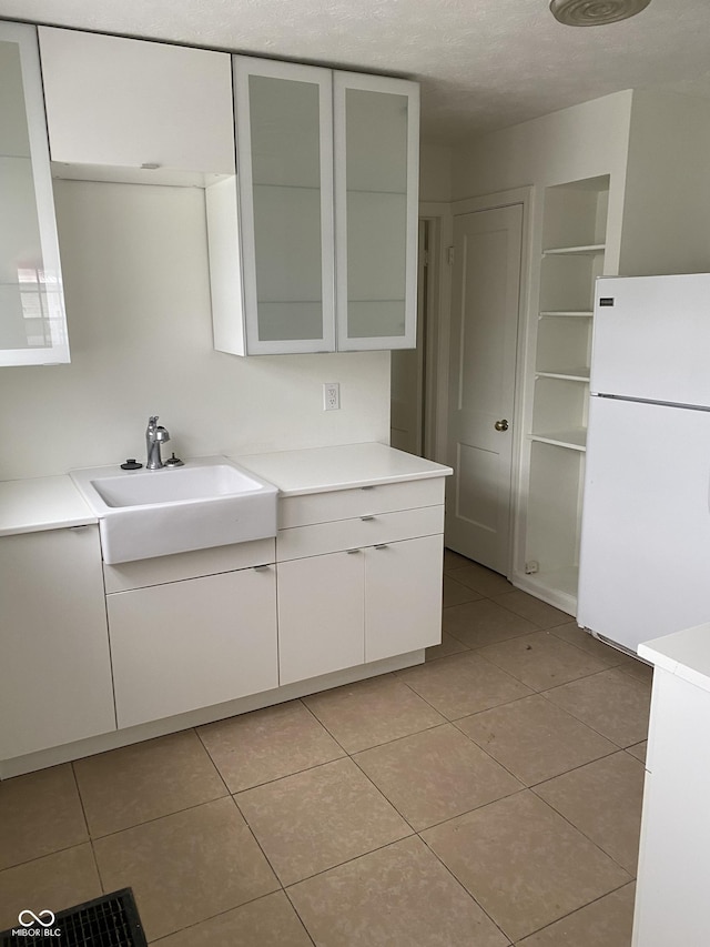 1444 N Denny St, Indianapolis, IN 46201 - kitchen featuring freestanding refrigerator, a sink, light countertops, white cabinets, and light tile patterned flooring