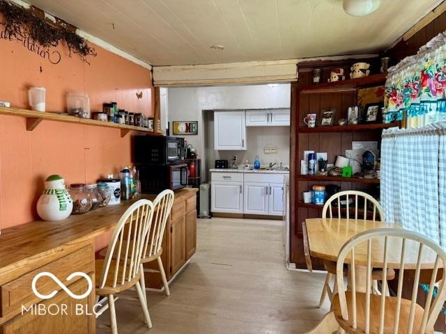 1118 S 2nd St, Lafayette, IN 47905 - kitchen featuring open shelves, black microwave, white cabinets, light wood-style floors, and a sink