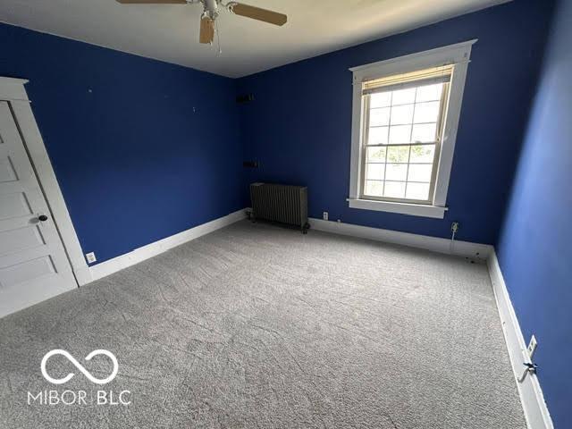 323 W 8th St, Rushville, IN 46173 - carpeted spare room featuring radiator, ceiling fan, and baseboards