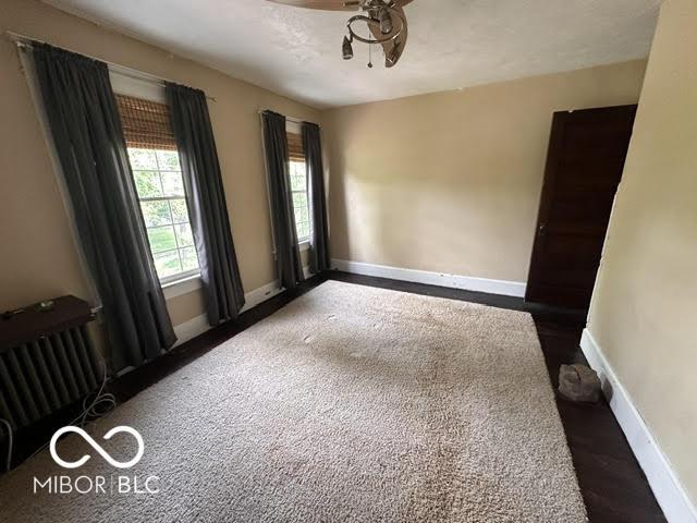323 W 8th St, Rushville, IN 46173 - unfurnished room with a ceiling fan, baseboards, and radiator heating unit
