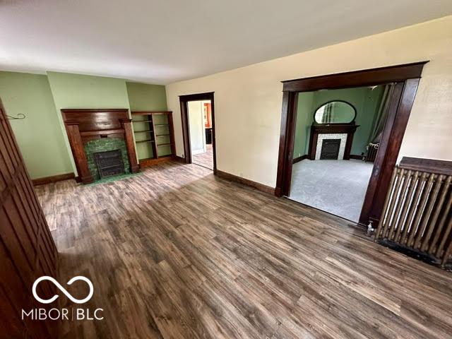 323 W 8th St, Rushville, IN 46173 - unfurnished living room with a fireplace with flush hearth, wood finished floors, and baseboards