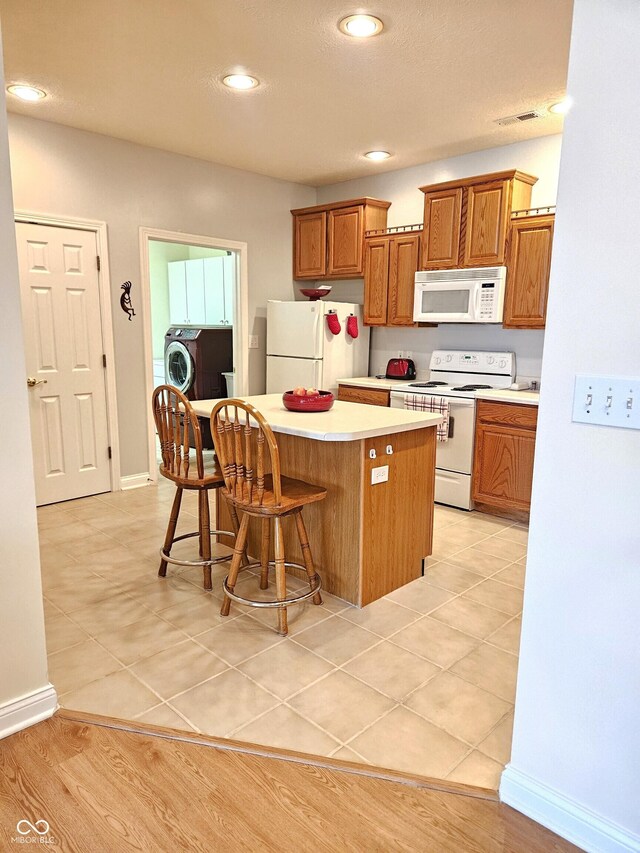 6956 Park Square Dr Unit D, Avon, IN 46123 - kitchen with white appliances, a kitchen island, light countertops, a kitchen bar, and brown cabinetry