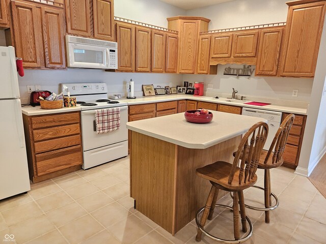 6956 Park Square Dr Unit D, Avon, IN 46123 - kitchen with white appliances, a sink, light countertops, and a kitchen breakfast bar