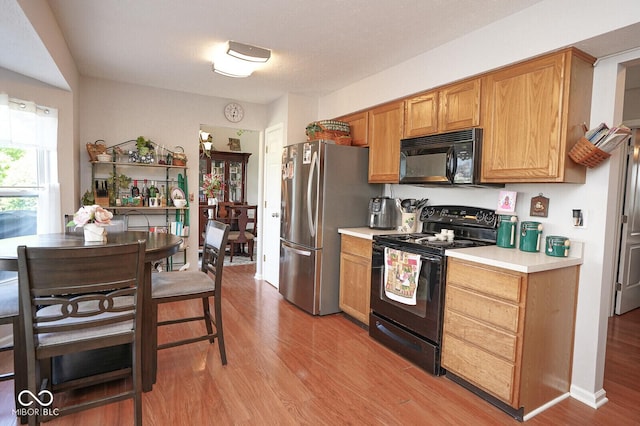 4342 Sequoia Ct, Greenwood, IN 46143 - kitchen with black appliances, light countertops, light wood finished floors, and brown cabinets