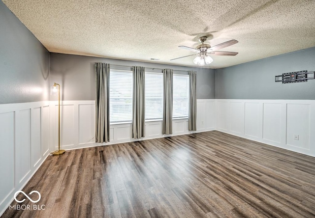 7657 Wheatgrass Ln, Noblesville, IN 46062 - spare room featuring a decorative wall, a ceiling fan, a wainscoted wall, a textured ceiling, and wood finished floors