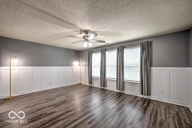 7657 Wheatgrass Ln, Noblesville, IN 46062 - spare room featuring a decorative wall, a ceiling fan, dark wood-style floors, a wainscoted wall, and a textured ceiling