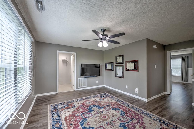 7657 Wheatgrass Ln, Noblesville, IN 46062 - unfurnished living room featuring a textured ceiling, plenty of natural light, ceiling fan, and dark wood-style floors