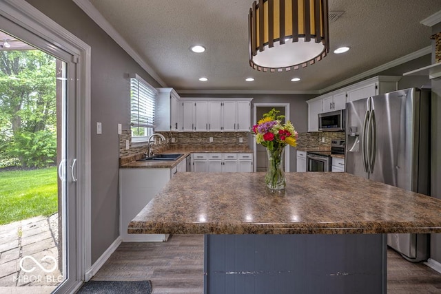 7657 Wheatgrass Ln, Noblesville, IN 46062 - kitchen with appliances with stainless steel finishes, a sink, ornamental molding, a textured ceiling, and dark wood-style floors