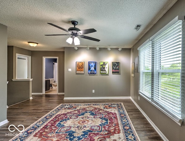 7657 Wheatgrass Ln, Noblesville, IN 46062 - empty room with rail lighting, a textured ceiling, dark wood finished floors, ceiling fan, and baseboards