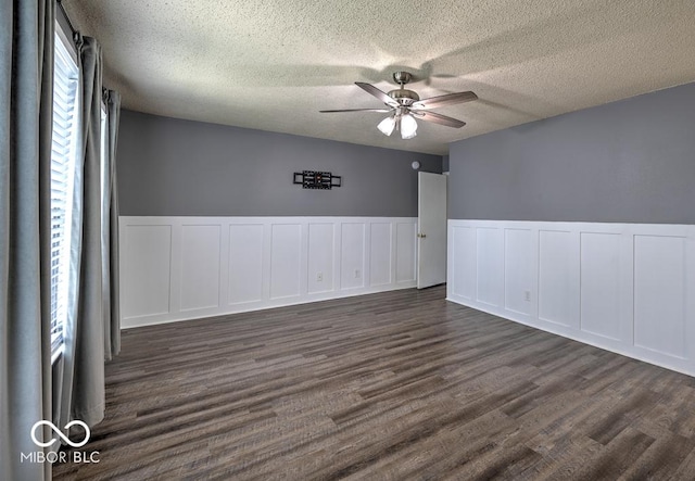7657 Wheatgrass Ln, Noblesville, IN 46062 - empty room featuring a ceiling fan, a decorative wall, a textured ceiling, dark wood-type flooring, and wainscoting