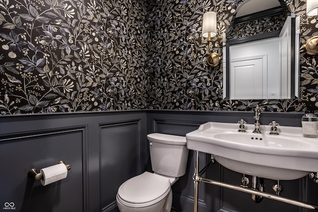 7105 Sylvan Ridge Rd, Indianapolis, IN 46240 - half bathroom with wallpapered walls, toilet, wainscoting, and a sink