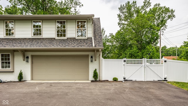 7105 Sylvan Ridge Rd, Indianapolis, IN 46240 - view of front of property with a gate, brick siding, a shingled roof, an attached garage, and asphalt driveway