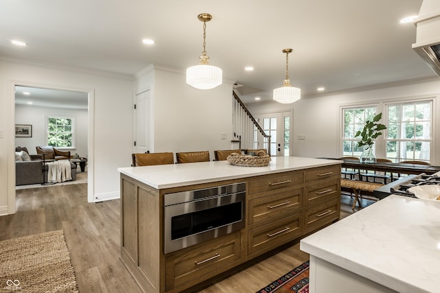 7105 Sylvan Ridge Rd, Indianapolis, IN 46240 - kitchen featuring hanging light fixtures, crown molding, light wood-style floors, recessed lighting, and a center island