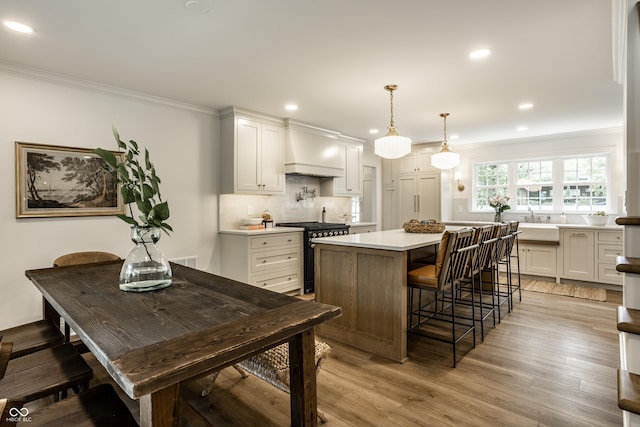 7105 Sylvan Ridge Rd, Indianapolis, IN 46240 - kitchen featuring range with gas cooktop, custom range hood, ornamental molding, a kitchen island, and backsplash