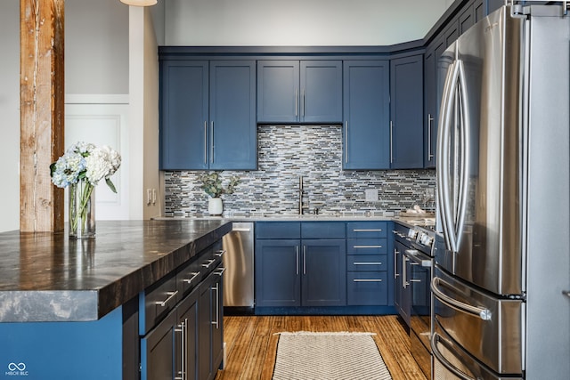 630 N College Ave Unit 409, Indianapolis, IN 46204 - kitchen featuring stainless steel appliances, a sink, tasteful backsplash, light wood finished floors, and blue cabinetry