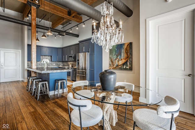 630 N College Ave Unit 409, Indianapolis, IN 46204 - dining area with dark wood finished floors, a towering ceiling, a chandelier, baseboards, and rail lighting