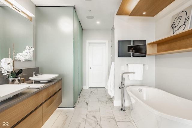 630 N College Ave Unit 409, Indianapolis, IN 46204 - bathroom with marble look tiles, a freestanding bath, double vanity, recessed lighting, and baseboards
