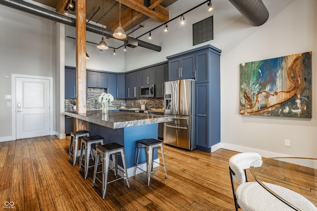630 N College Ave Unit 409, Indianapolis, IN 46204 - kitchen featuring appliances with stainless steel finishes, a towering ceiling, a breakfast bar area, rail lighting, and dark countertops