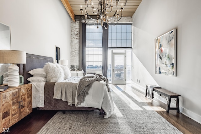 630 N College Ave Unit 409, Indianapolis, IN 46204 - bedroom featuring wood ceiling with exposed beams, a towering ceiling, a chandelier, wood finished floors, and baseboards