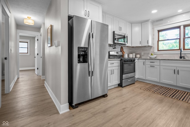 2537 N Boehning St, Indianapolis, IN 46219 - kitchen with stainless steel appliances, baseboards, white cabinets, light wood-type flooring, and recessed lighting
