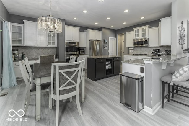 2502 Colinbrook Pkwy, Greenwood, IN 46143 - kitchen with stainless steel appliances, a chandelier, recessed lighting, decorative backsplash, and light wood-style flooring