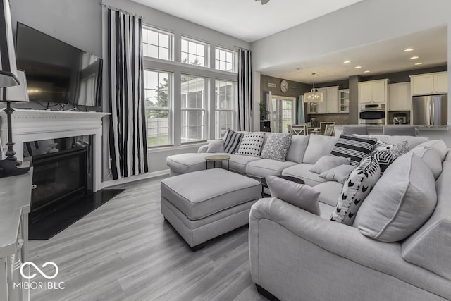 2502 Colinbrook Pkwy, Greenwood, IN 46143 - living room featuring plenty of natural light, recessed lighting, light wood-type flooring, a premium fireplace, and a chandelier
