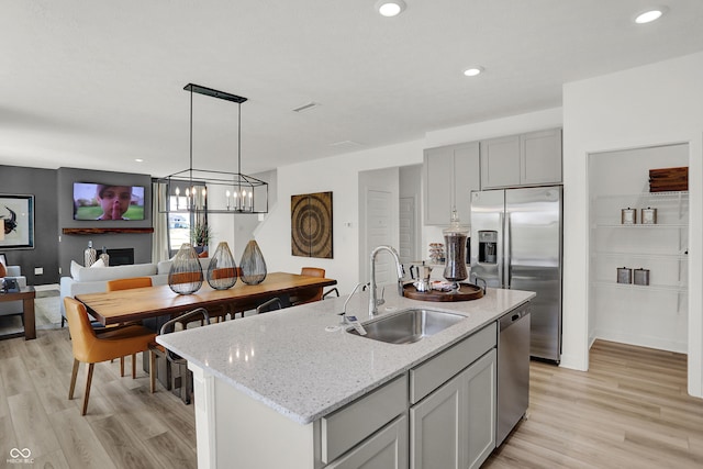 942 Shadow Dr, Danville, IN 46122 - kitchen featuring a sink, appliances with stainless steel finishes, light wood-style flooring, light stone countertops, and a chandelier