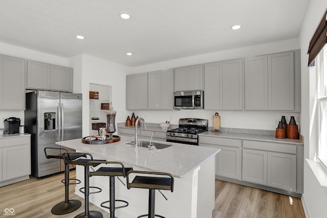 942 Shadow Dr, Danville, IN 46122 - kitchen featuring stainless steel appliances, a sink, gray cabinetry, light wood-type flooring, and light stone countertops