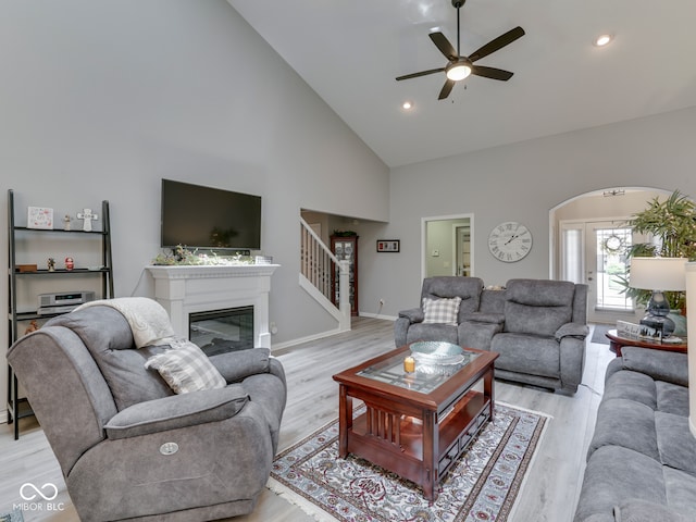 5351 Abbington Ave, Plainfield, IN 46168 - living room featuring high vaulted ceiling, a ceiling fan, light wood-style flooring, arched walkways, and a glass covered fireplace