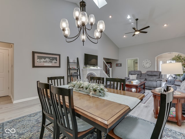 5351 Abbington Ave, Plainfield, IN 46168 - dining area featuring high vaulted ceiling, light wood finished floors, ceiling fan, a fireplace, and a skylight