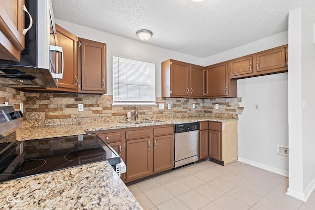 1903 Windy Hill Ln, Indianapolis, IN 46239 - kitchen featuring appliances with stainless steel finishes, tasteful backsplash, brown cabinets, a textured ceiling, and light tile patterned floors