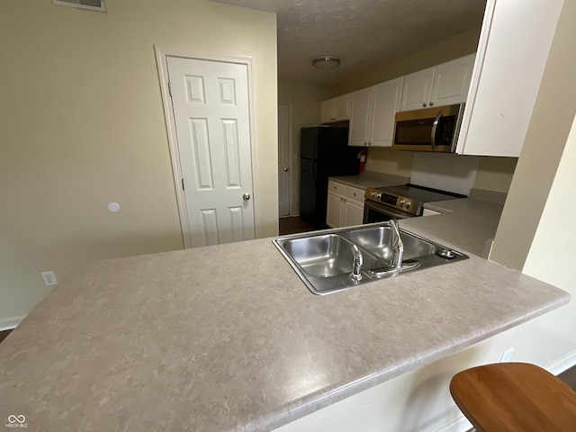 2853 S Walnut Street Pike, Bloomington, IN 47401 - kitchen featuring appliances with stainless steel finishes, white cabinetry, light countertops, and a peninsula