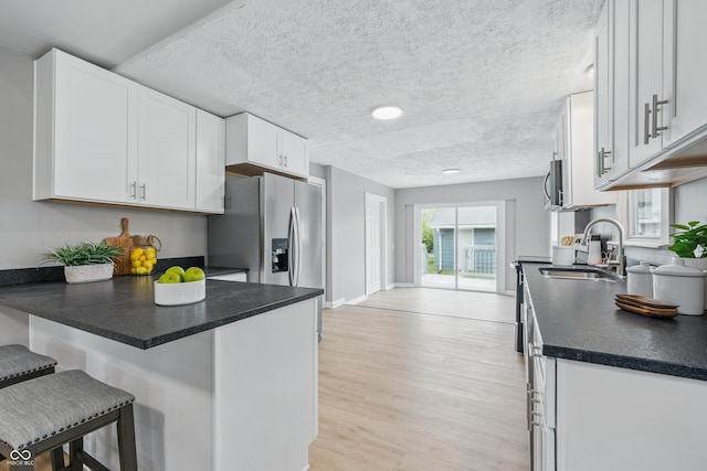 3906 Fletcher Ave, Indianapolis, IN 46203 - kitchen with a sink, a breakfast bar, white cabinets, dark countertops, and a peninsula