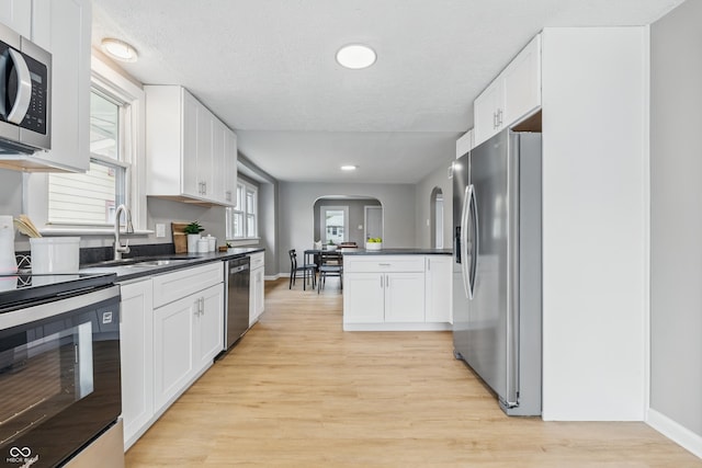 3906 Fletcher Ave, Indianapolis, IN 46203 - kitchen with appliances with stainless steel finishes, arched walkways, dark countertops, light wood-style floors, and recessed lighting