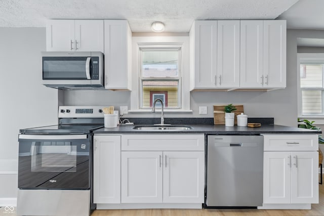 3906 Fletcher Ave, Indianapolis, IN 46203 - kitchen with stainless steel appliances, a sink, a textured ceiling, dark countertops, and white cabinetry