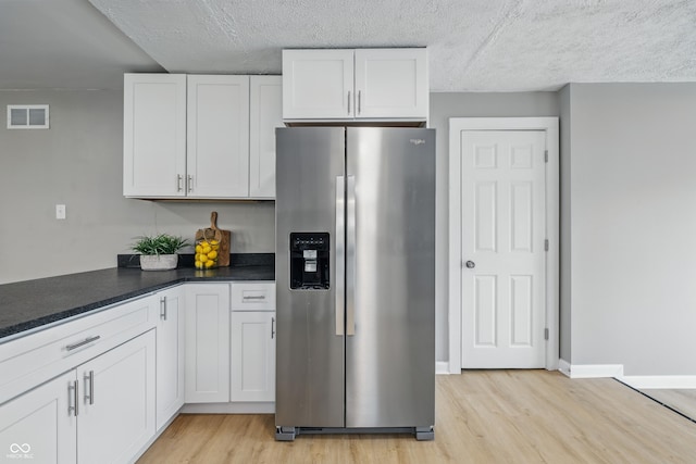 3906 Fletcher Ave, Indianapolis, IN 46203 - kitchen with stainless steel fridge with ice dispenser, light wood-style floors, white cabinetry, and a textured ceiling