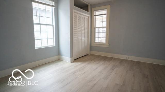 352 W 28th St, Indianapolis, IN 46208 - unfurnished bedroom featuring wood finished floors, multiple windows, baseboards, and a closet