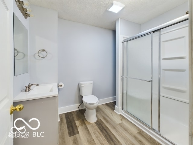 352 W 28th St, Indianapolis, IN 46208 - full bathroom with vanity, toilet, wood finished floors, a stall shower, and a textured ceiling