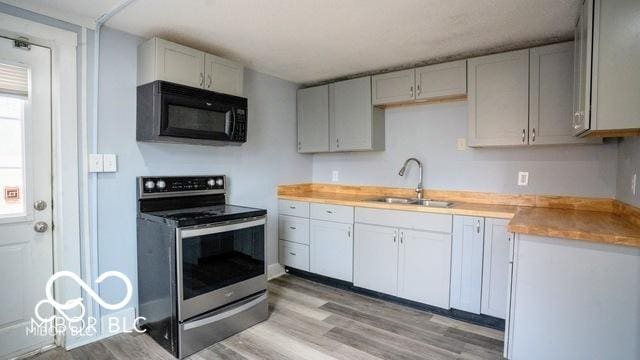 352 W 28th St, Indianapolis, IN 46208 - kitchen with black microwave, stainless steel electric range oven, a sink, and light wood-style flooring