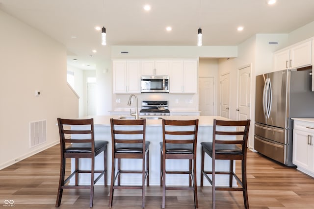 640 Axford Bay Dr, Westfield, IN 46074 - kitchen featuring appliances with stainless steel finishes, wood finished floors, a center island with sink, light countertops, and white cabinetry