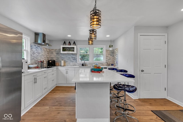 1618 Villa Ave, Indianapolis, IN 46203 - kitchen featuring stainless steel fridge, wall chimney exhaust hood, a kitchen bar, a sink, and tasteful backsplash