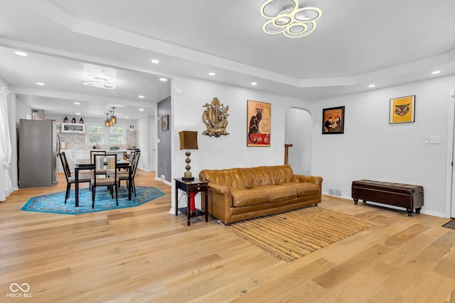 1618 Villa Ave, Indianapolis, IN 46203 - living area featuring arched walkways, recessed lighting, light wood-type flooring, a tray ceiling, and baseboards