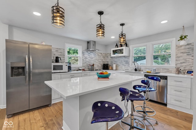 1618 Villa Ave, Indianapolis, IN 46203 - kitchen featuring appliances with stainless steel finishes, wall chimney exhaust hood, decorative backsplash, a kitchen bar, and recessed lighting